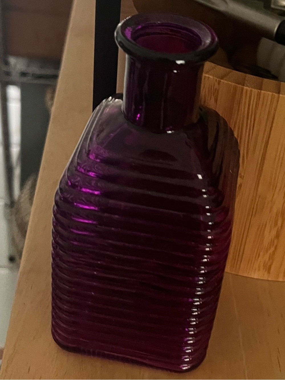 Purple glass bottle with a square, ribbed design and a narrow neck, New